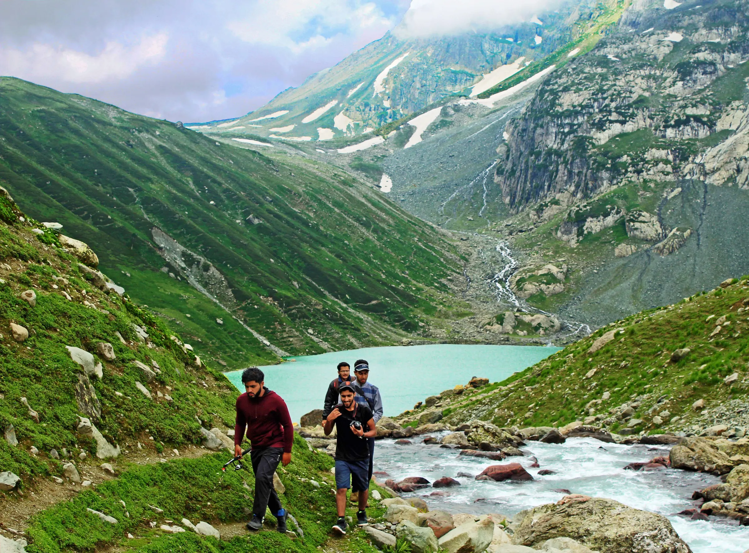 Trekkers beside a glacial lake below the snow line