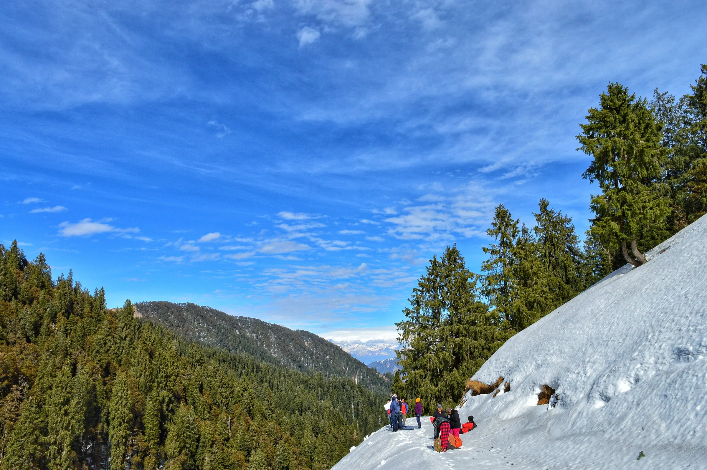 Trekkers crossing a snowfield with poles and packs